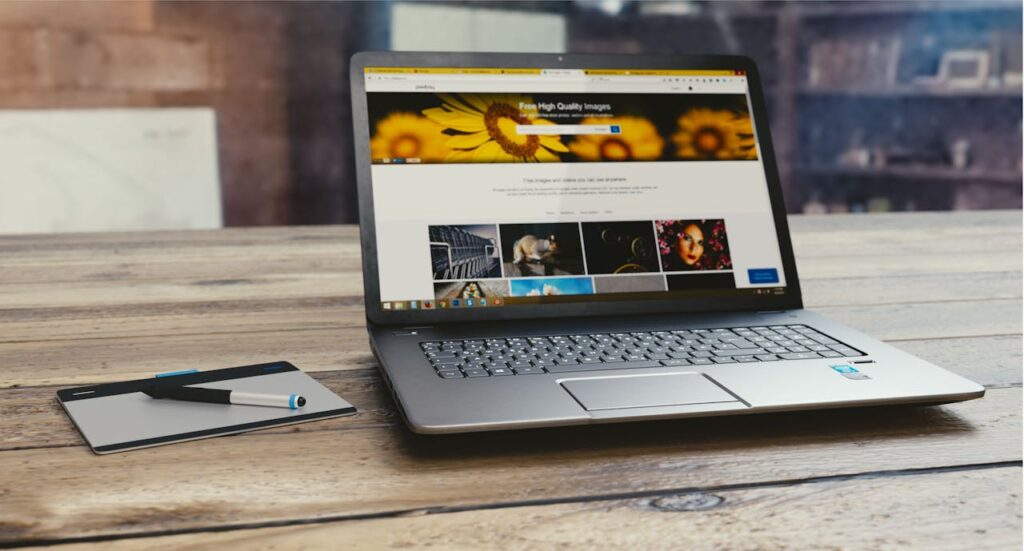 pexels photo 109371 Laptop with open webpage on wooden desk, accompanied by tablet and pen, representing digital work setup.