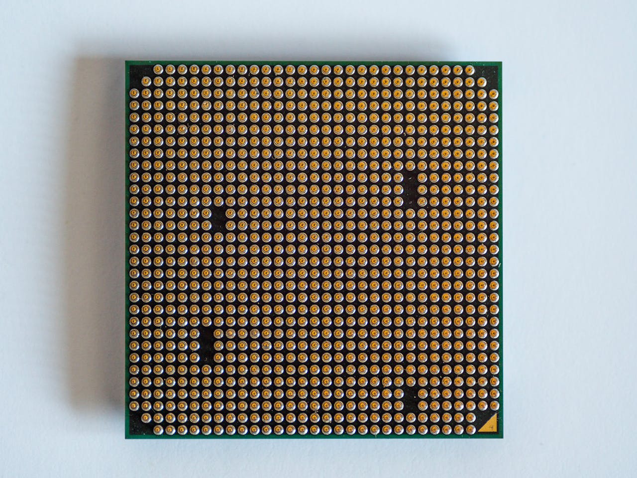 about-02 Detailed view of a computer processor, showcasing its pins, against a clean white backdrop.